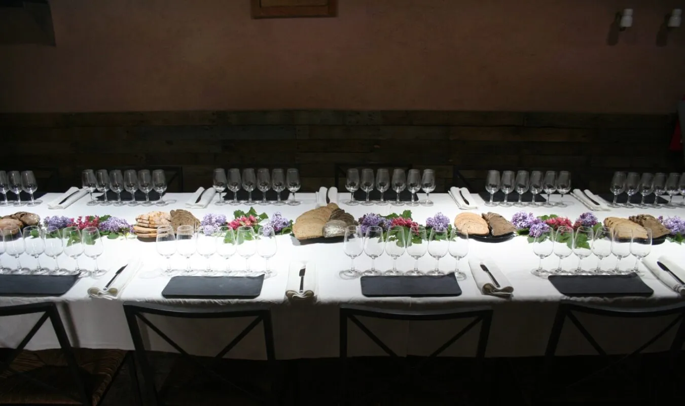 Mesa de cata de vinos preparada para grupo en interior de masía con copas y pan artesano