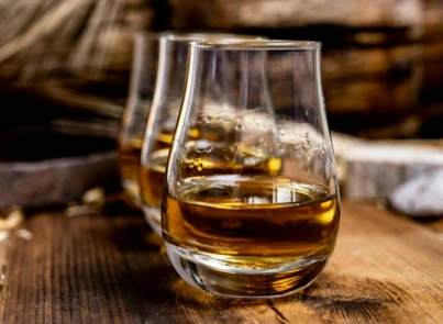 Dos copas Glencairn con whisky single malt sobre madera rústica en cata de destilados