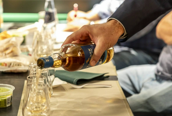 Mano sirviendo whisky premium en vaso tumbler durante cata de destilados en Barcelona