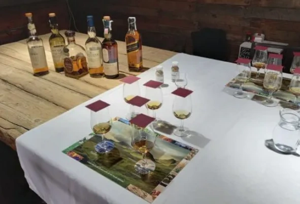 Mesa de taller de whisky con copas servidas, fichas de regiones y botellas en Can Tomàs Bassa